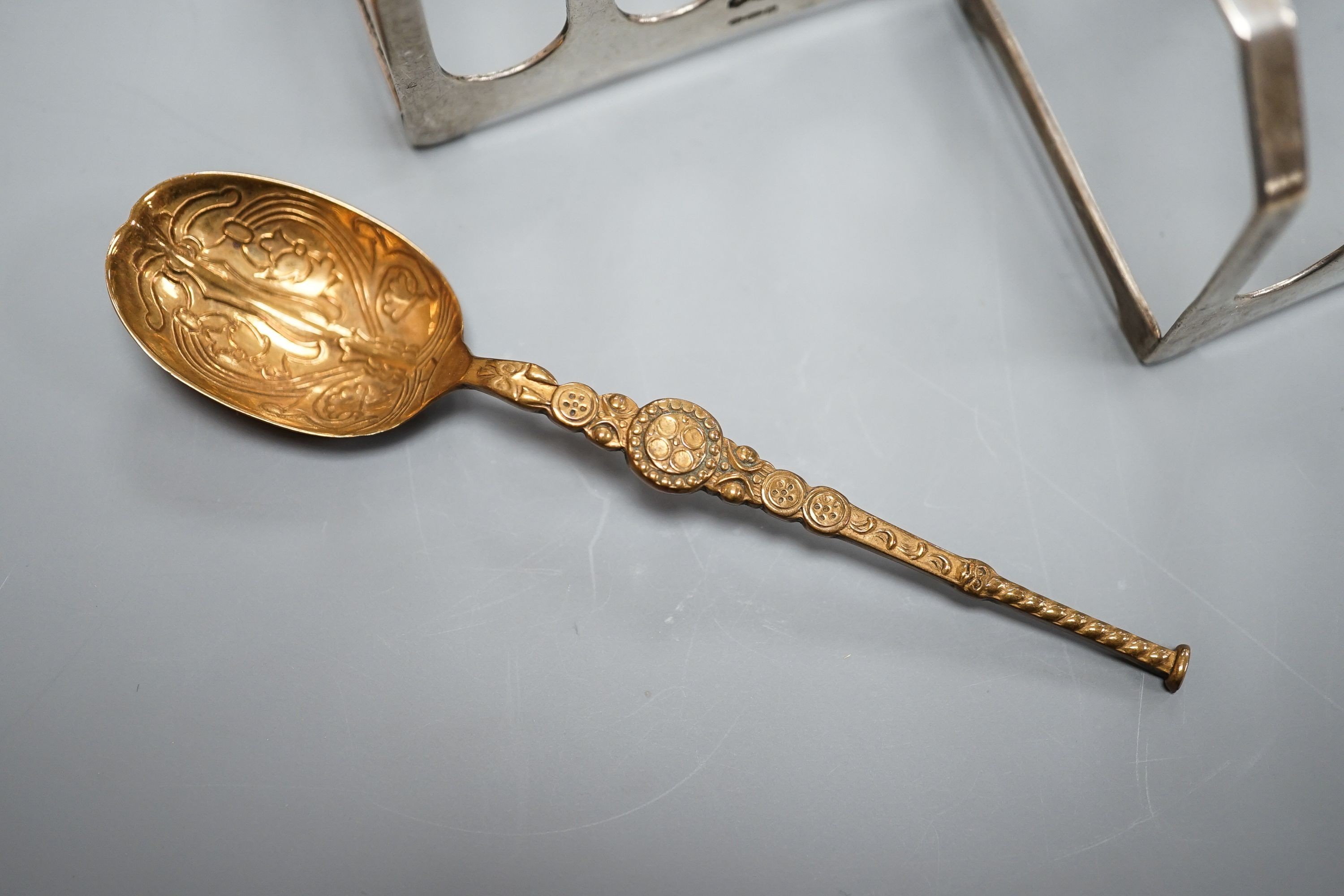 A pair of George VI silver five bar toastracks, Viner's Ltd, Sheffield, 1937, length 76mm and metal replica of a 12th century Coronation spoon.
